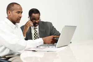 Two business men calling their accountant while looking at a laptop