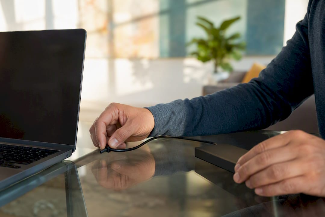 Hands connecting external drive to laptop